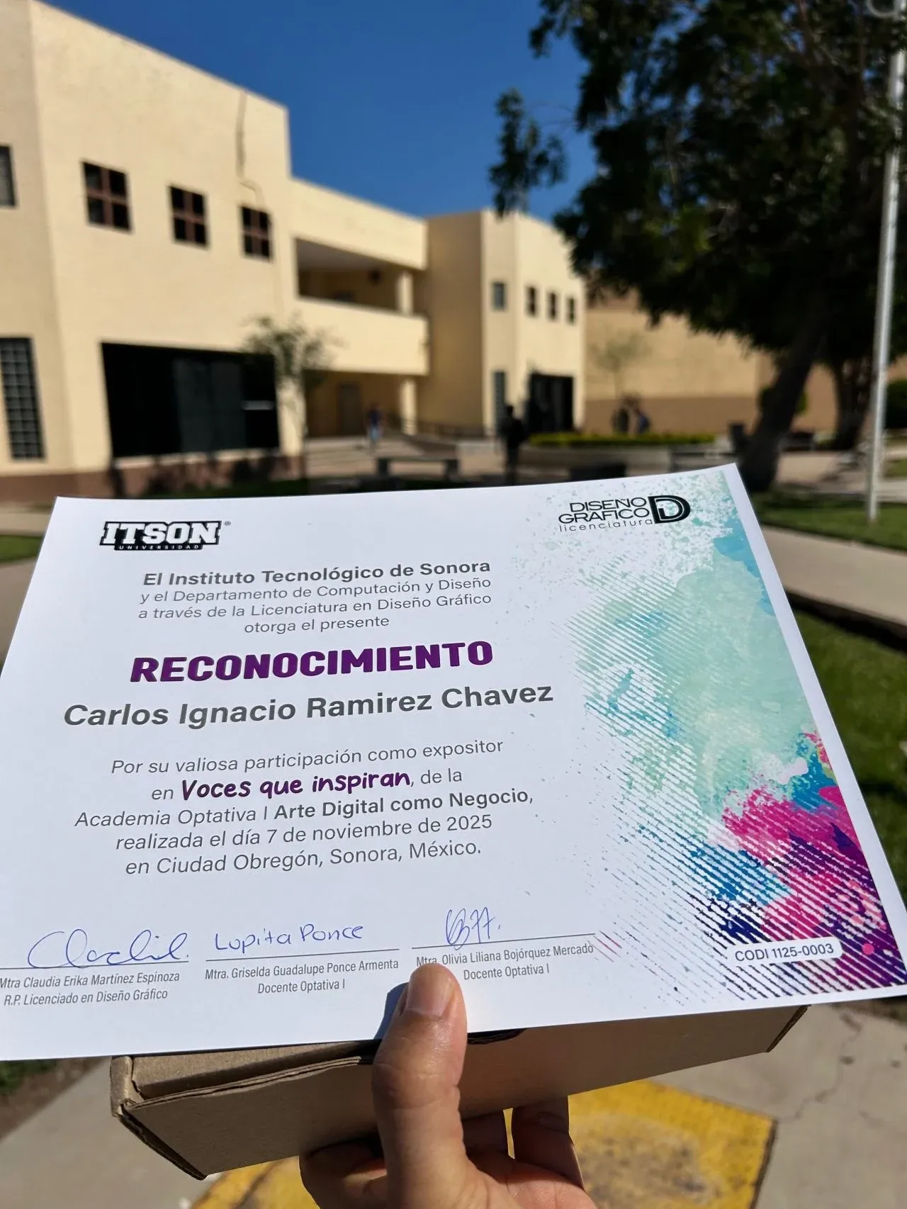 Reconocimiento del ITSON a Carlos Ramírez como expositor en Voces que inspiran, frente a un edificio del campus